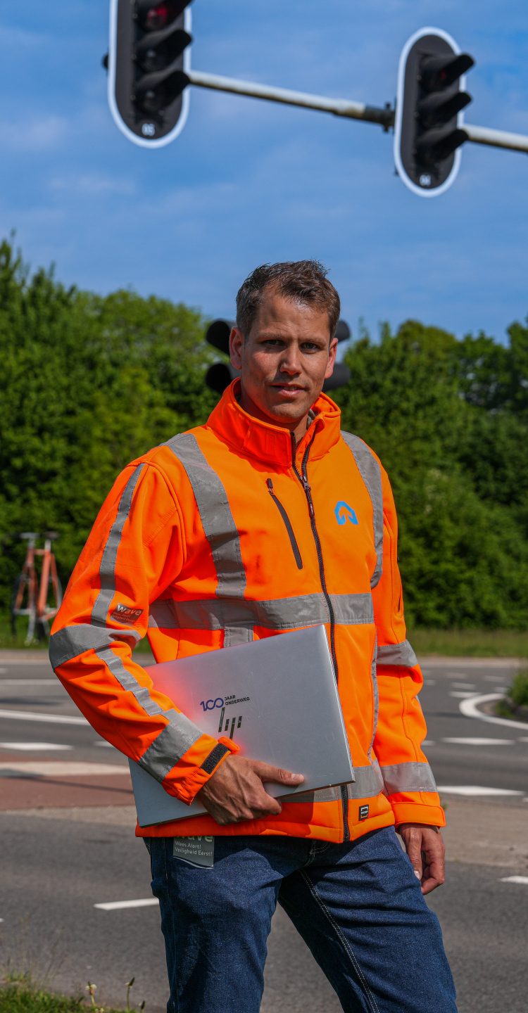 Medewerker van ViaMobility staat op een kruispunt met laptop in zijn arm