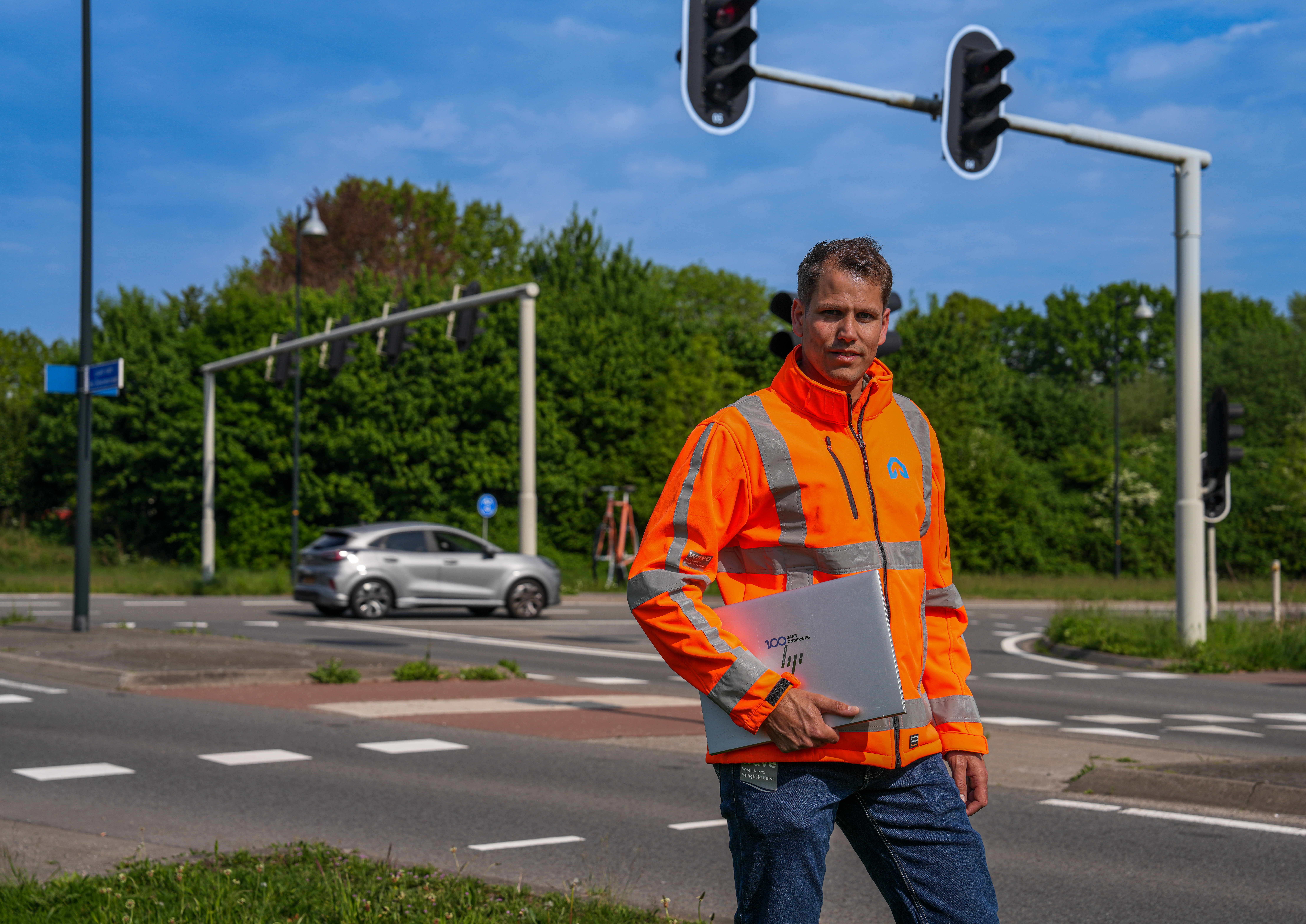 Medewerker van ViaMobility staat op een kruispunt met laptop in zijn arm